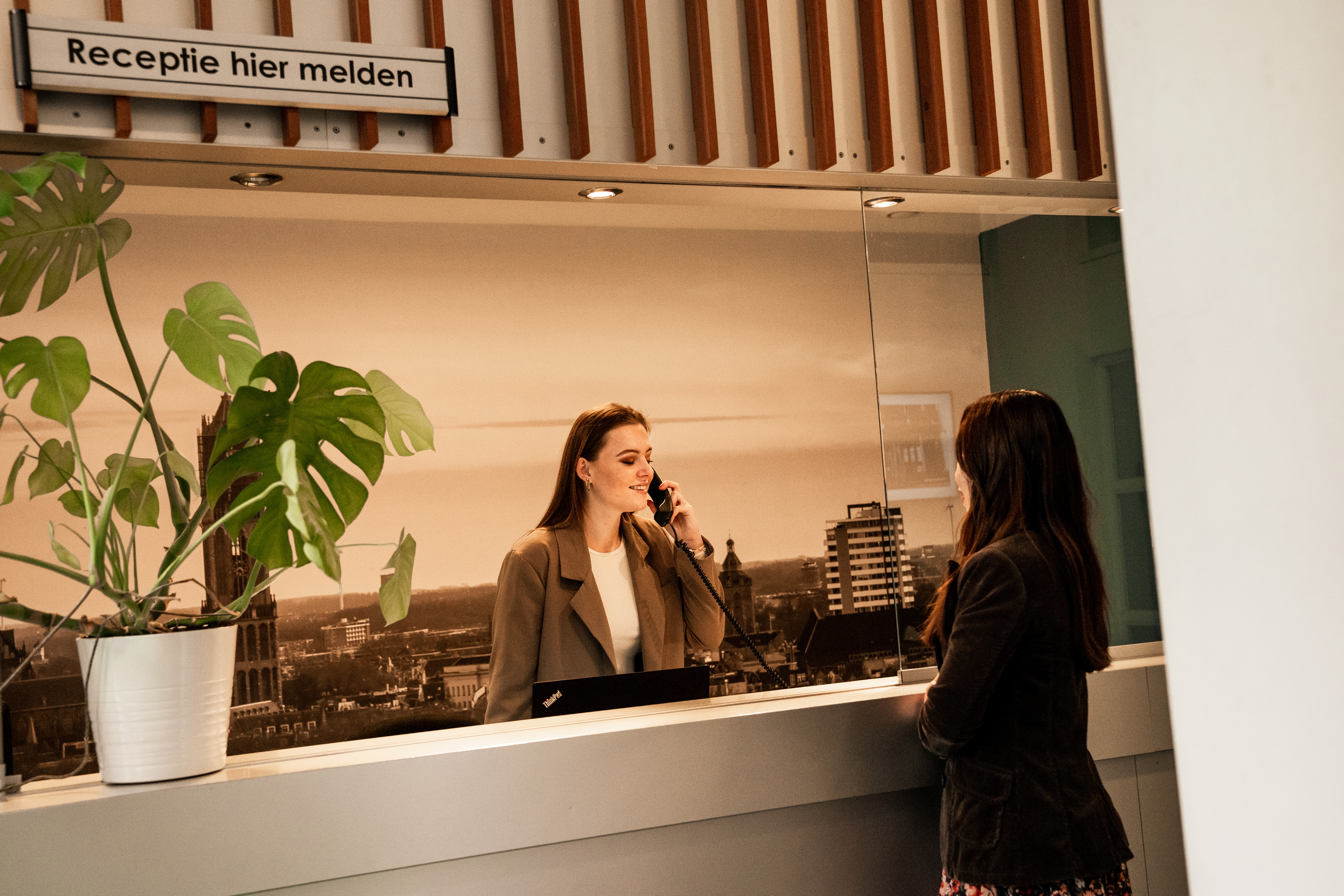 Receptionist aan de telefoon met gast.jpg